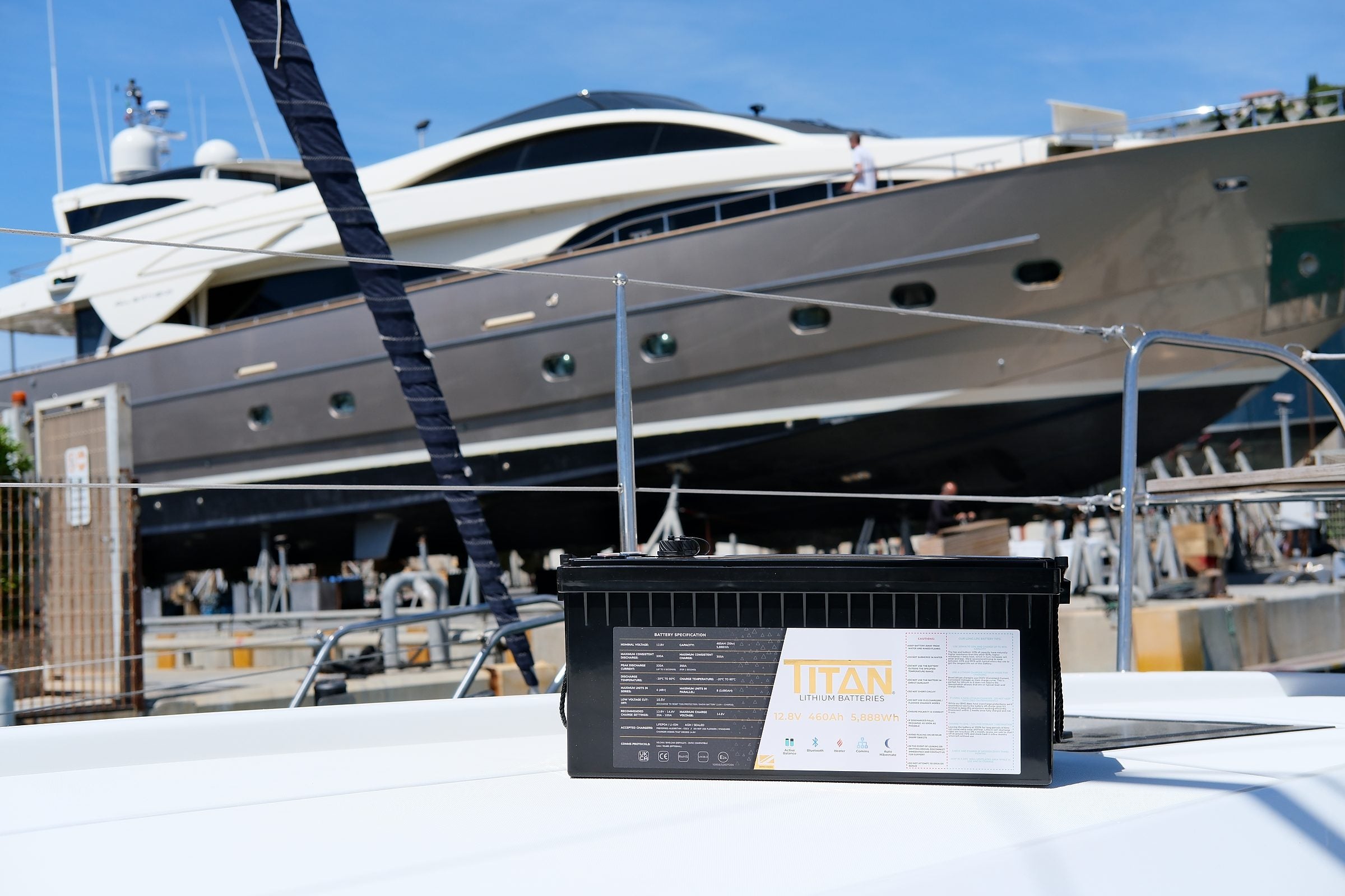 A TITAN 460Ah lithium battery on a marina dock with a large motor yacht moored behind